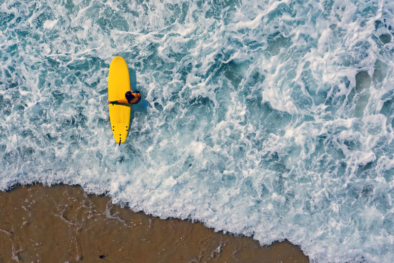 High angle view of person with surfboard in sea