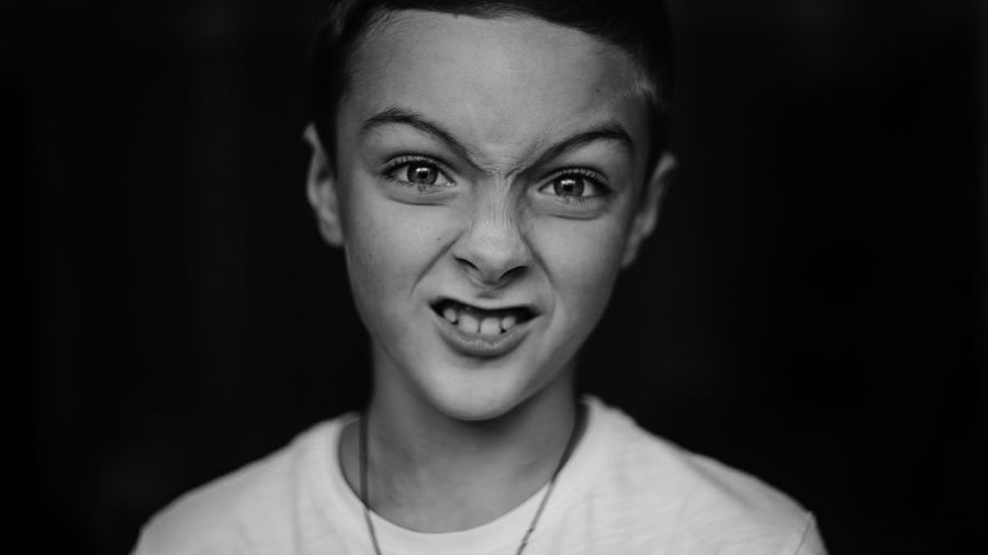 Portrait of boy making funny face against black background