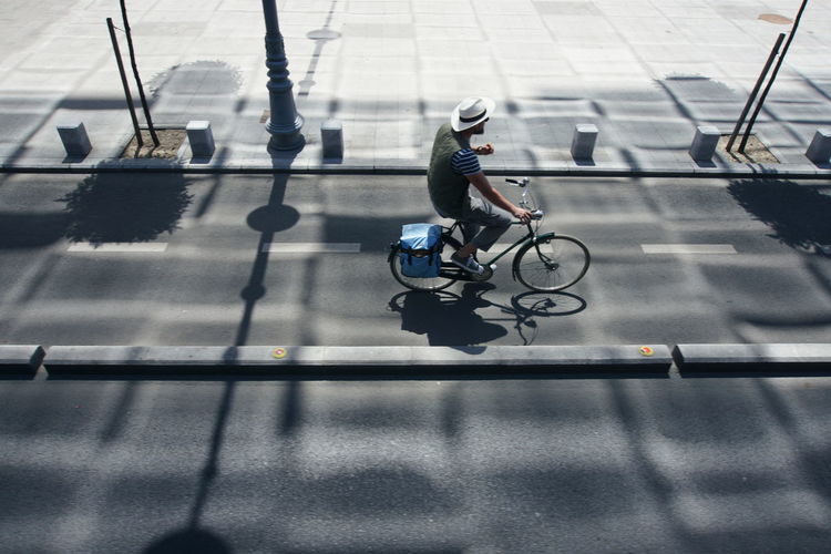High angle view of man riding bicycle on road during sunny day