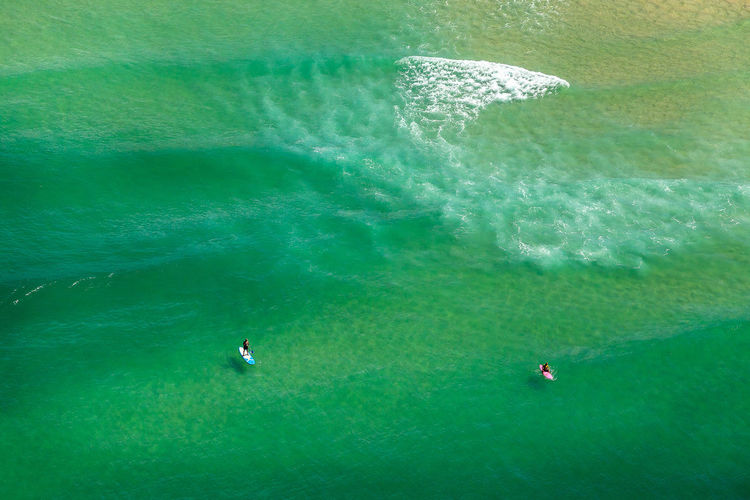 High angle view of friends paddleboarding in sea