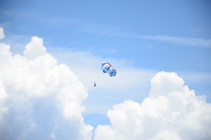 People paragliding against cloudy sky