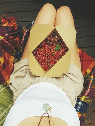 High angle view of woman with cherry box on lap