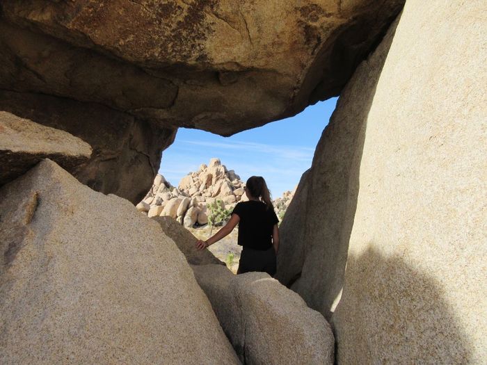 Rear view of woman standing amidst rocks
