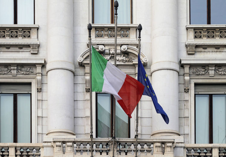 Italian flag hanging down next to eu flag in the wind