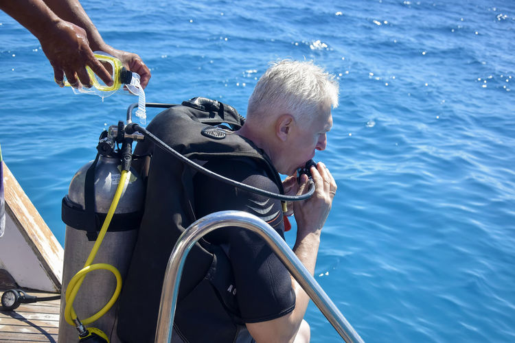Scuba diver before diving. male in scuba diving suit is preparing to dive into deep sea.