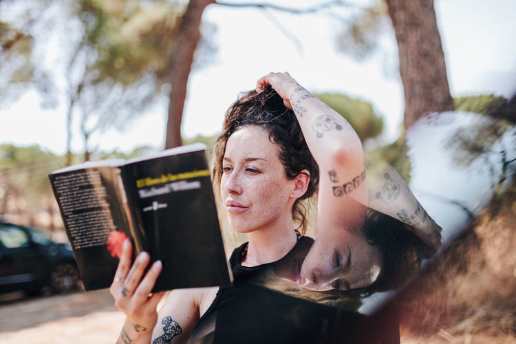 Woman reading book while sitting outdoors