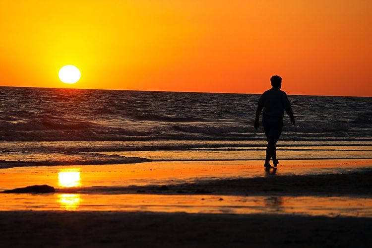 Silhouette man standing on beach during sunset