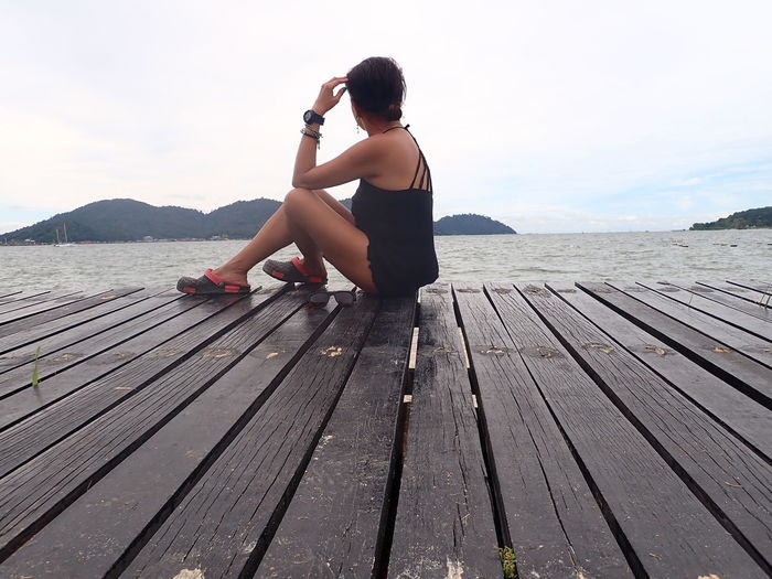 Woman sitting on wooden pier