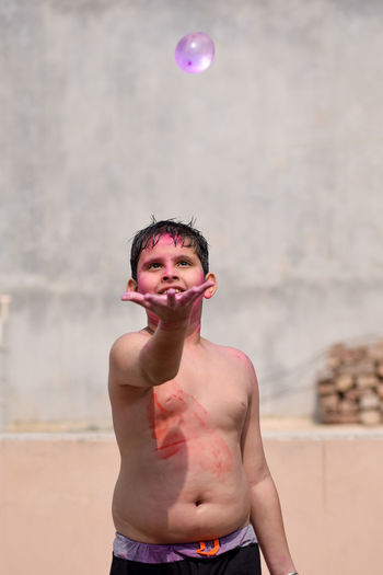 Shirtless boy playing with water bomb during holi