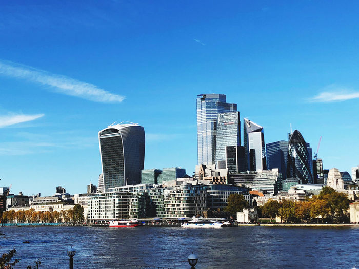 Modern buildings by river against sky in london city