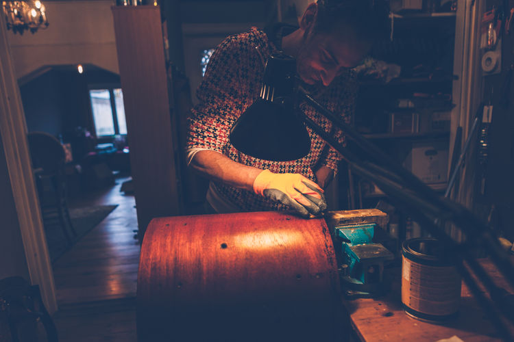 Man polishing wooden container on table at home