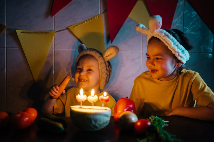 Vegetarian cake with candles birthday vegetables kids in bunny ears girl crying. high quality photo