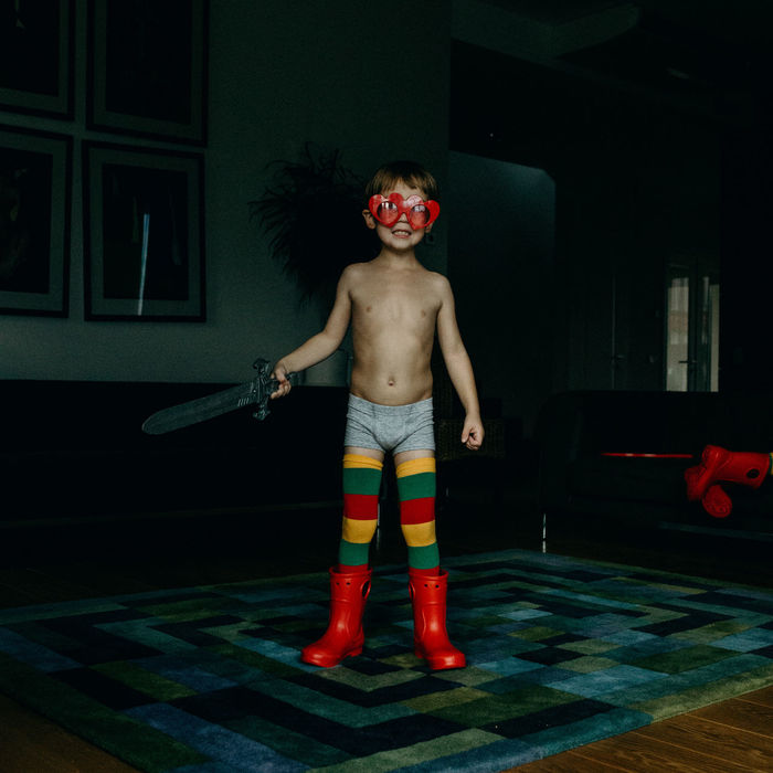 Full length of shirtless boy playing with sword toy at home