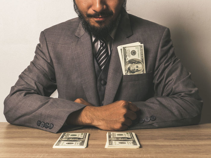 Midsection of businessman with paper currency at table