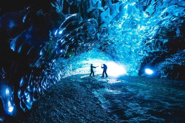 Side view of friends playing inside ice cave