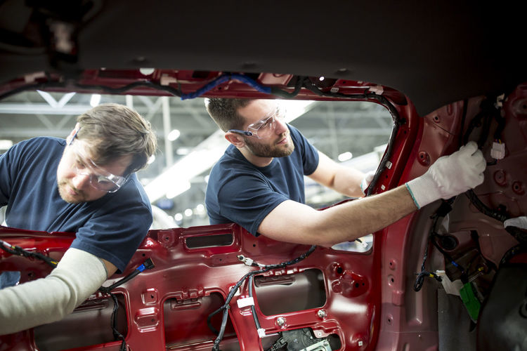 Two colleagues working at bodywork in modern car factory