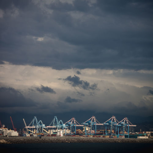 View of cranes at harbor against sky