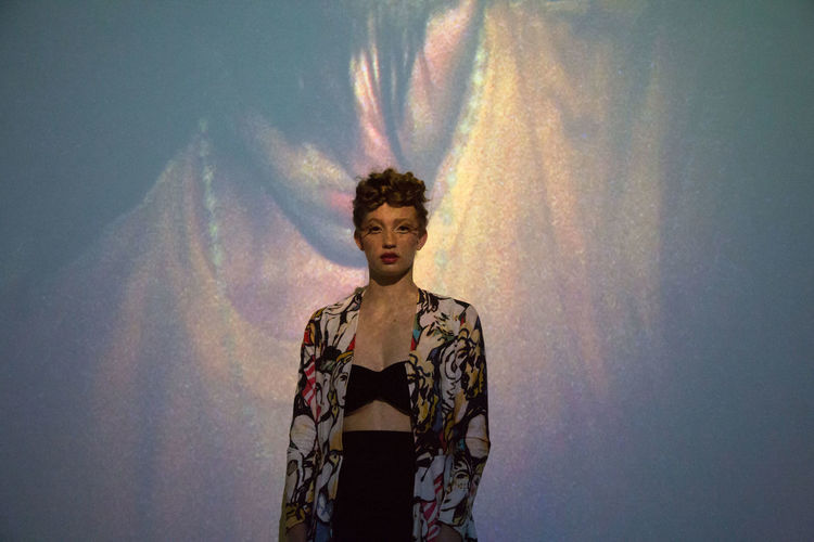 Portrait of fashion model standing against projection screen
