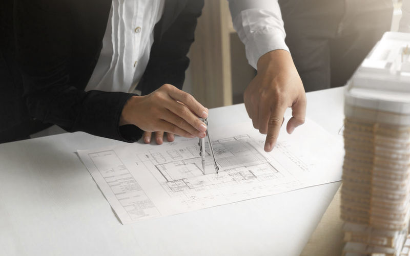 Midsection of architects working on blueprint in office