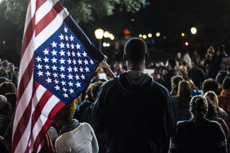 Rear view of man holding american flag in crowd