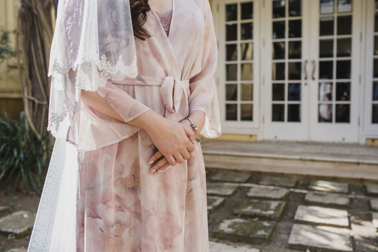 Midsection of woman standing by building on her wedding day