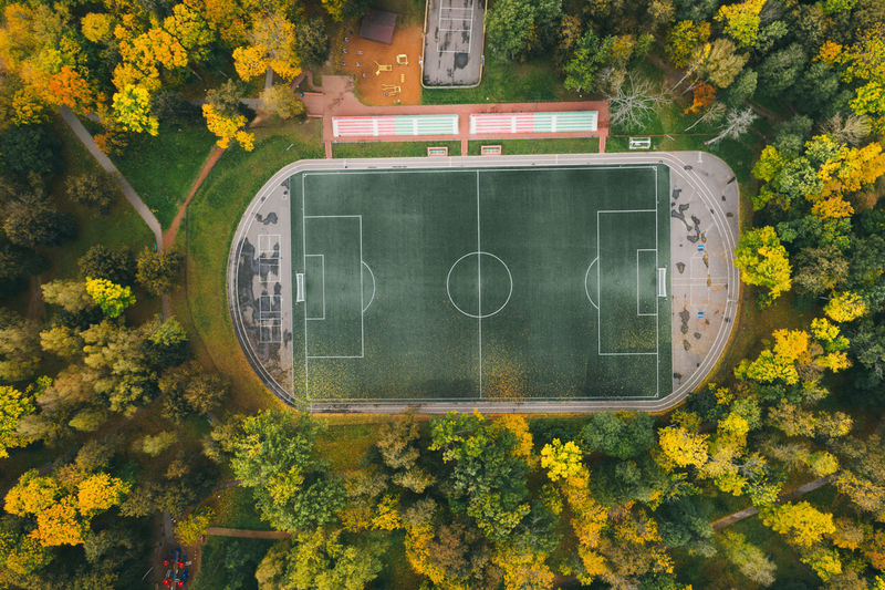 Football pitch surrounded by autumn forest, aerial view