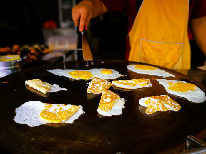 A restaurant worker is making fried eggs on a large skillet.