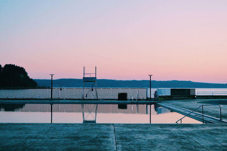 Swimming pool against sky during sunset