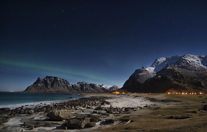 Scenic view of sea and mountains against sky at night