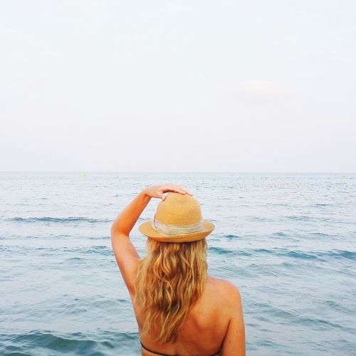 Rear view of woman in hat against sea