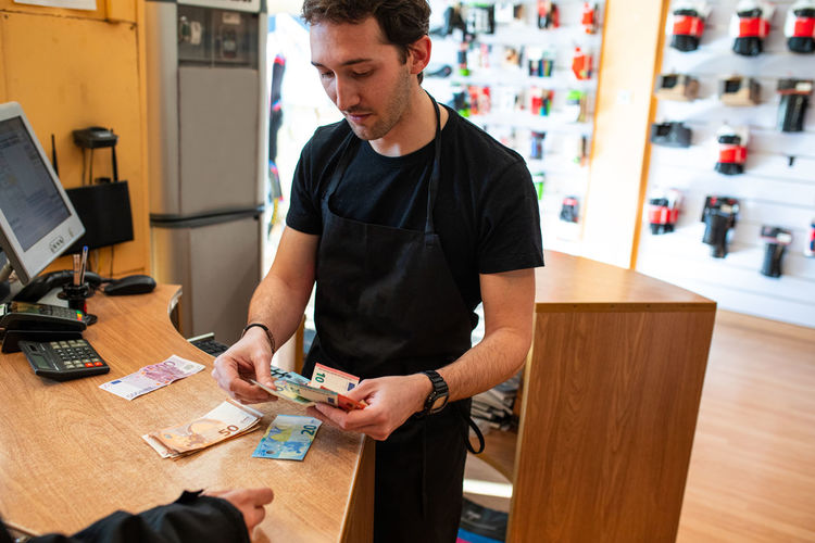 Salesman counting cash over counter for crop customer in modern store
