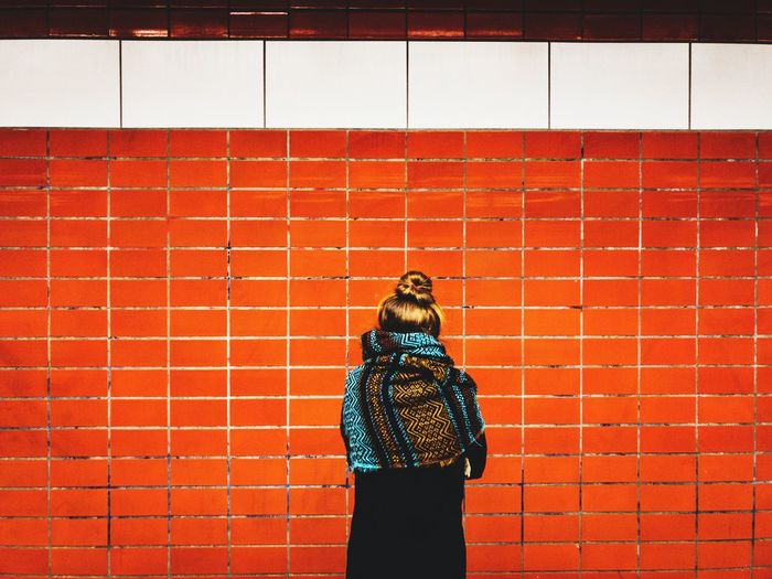 Rear view of woman standing against red brick wall