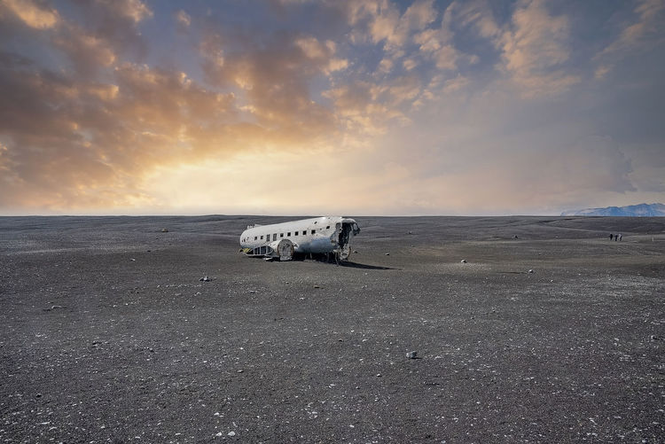 View of damaged airplane wreck at black sand beach in solheimasandur in sunset