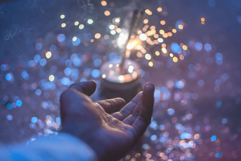 Cropped hand gesturing against illuminated sparkler