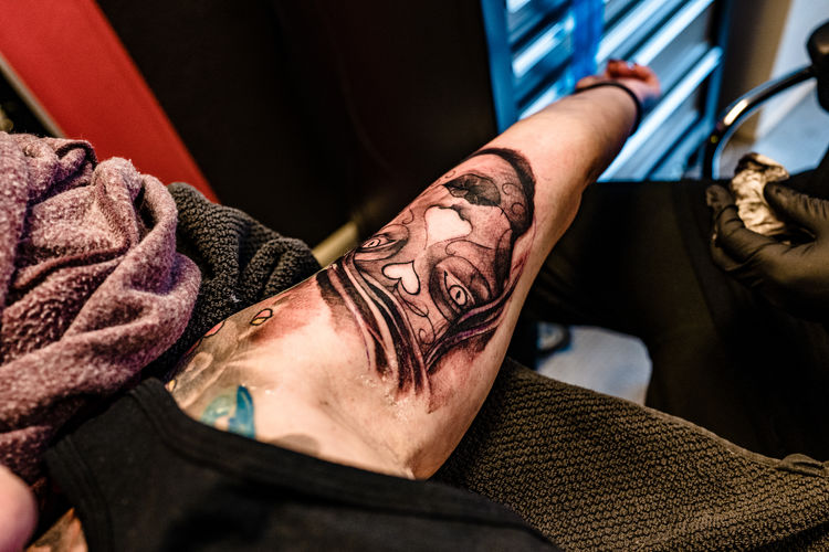 Close-up of artist tattooing design on human skin