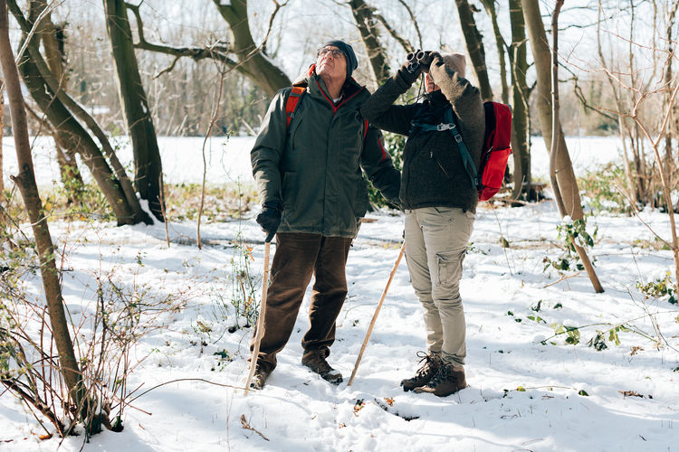 Front view of a senior couple in a snowy forest for bird watching