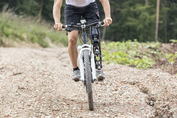 Low section of man riding bicycle on footpath
