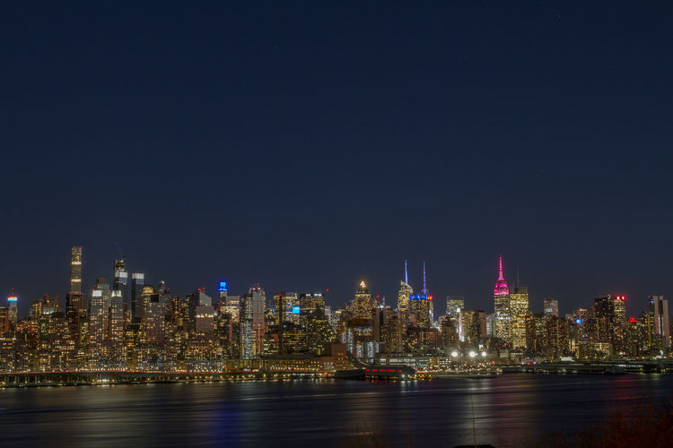 Illuminated buildings in city against sky at night