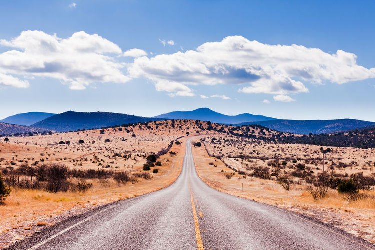 Road amidst desert land against sky
