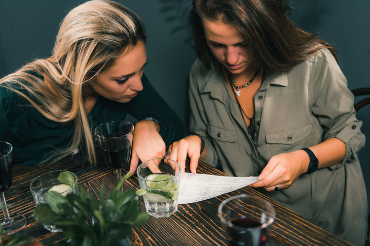 Female friends looking at paper in restaurant