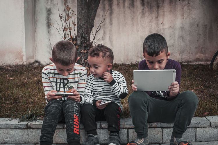 Friends looking at camera while sitting on mobile phone