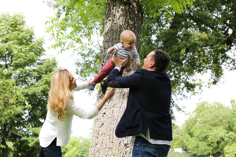 Father and mother playing with son near tree trunk