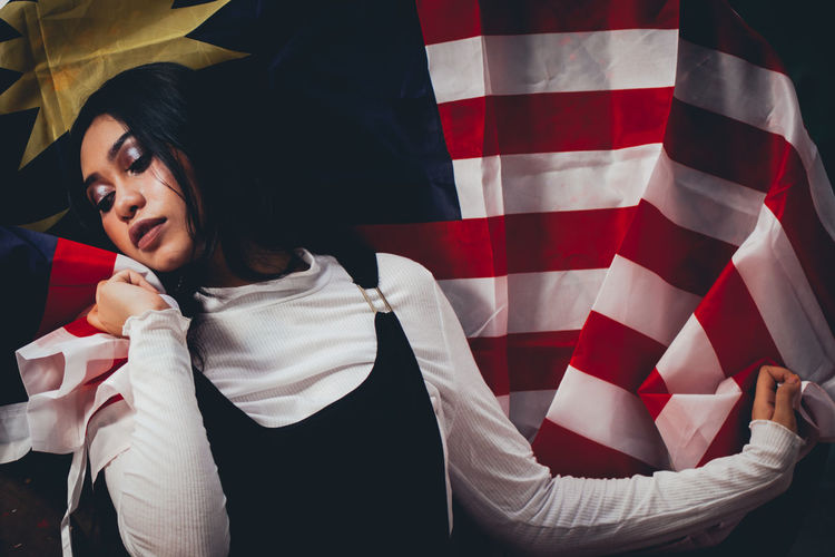 Thoughtful female model posing with malaysian flag on spool