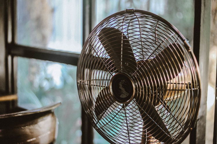 Close-up of vintage electric fan by window at home