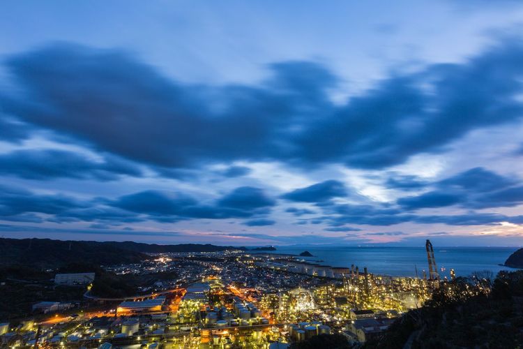 Aerial view of illuminated buildings against sky cloudy at dusk