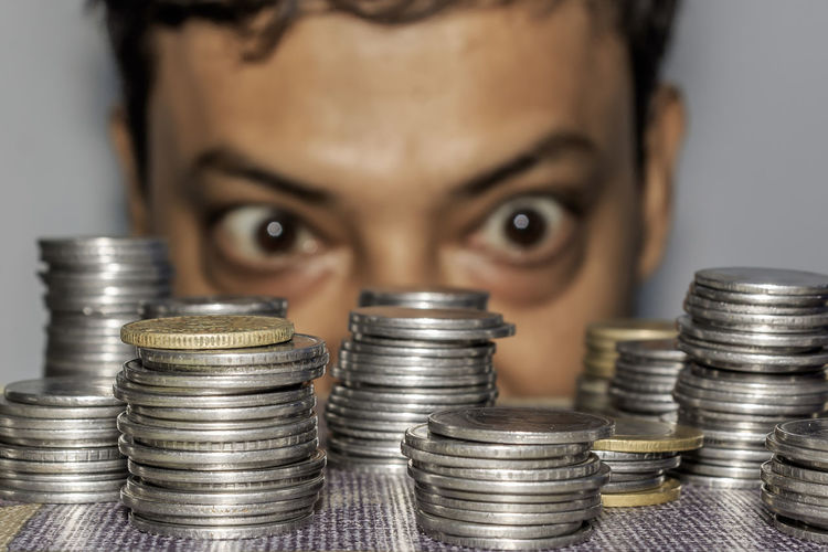 Close-up of coins stacks on table with man looking