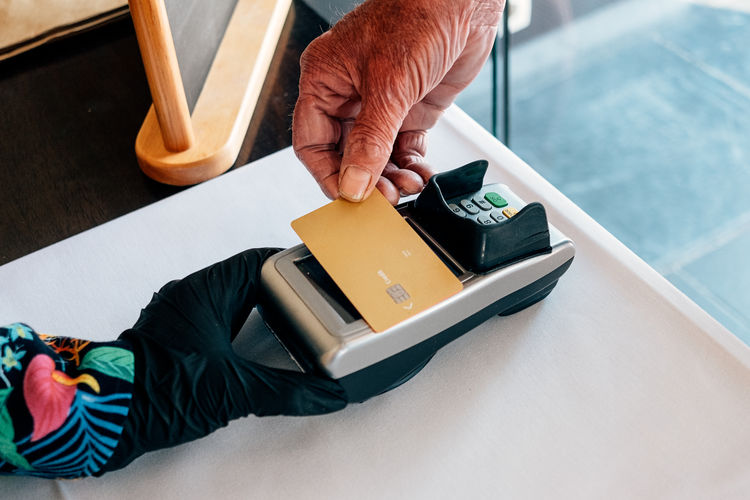 Close up old male hand holding card for electronic payment on terminal