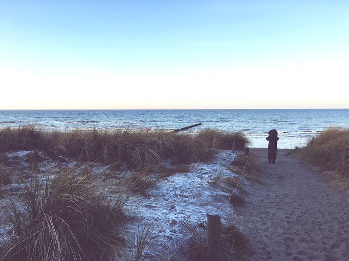Man standing on beach against clear sky