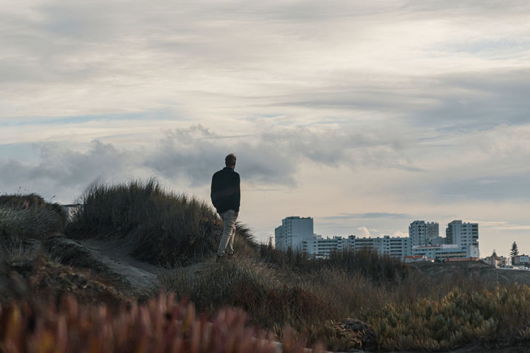 Man standing by cityscape against sky
