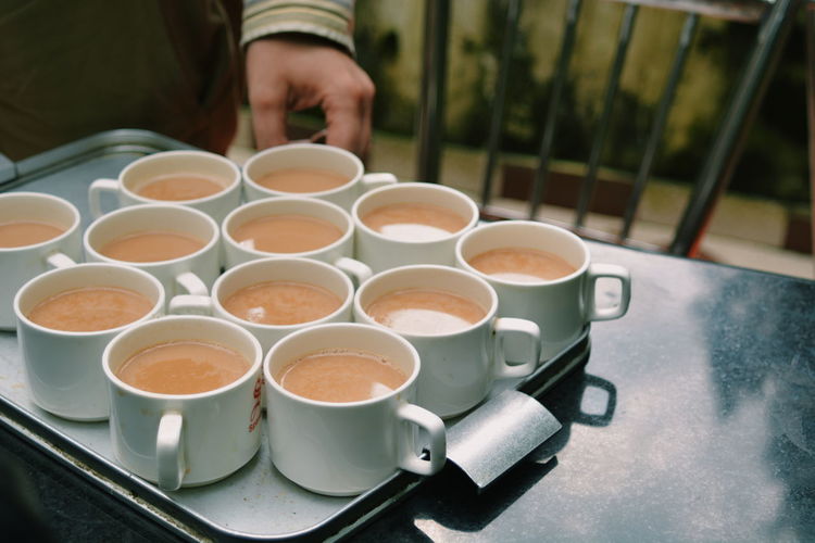 Midsection of man hand by tea cups in tray on table